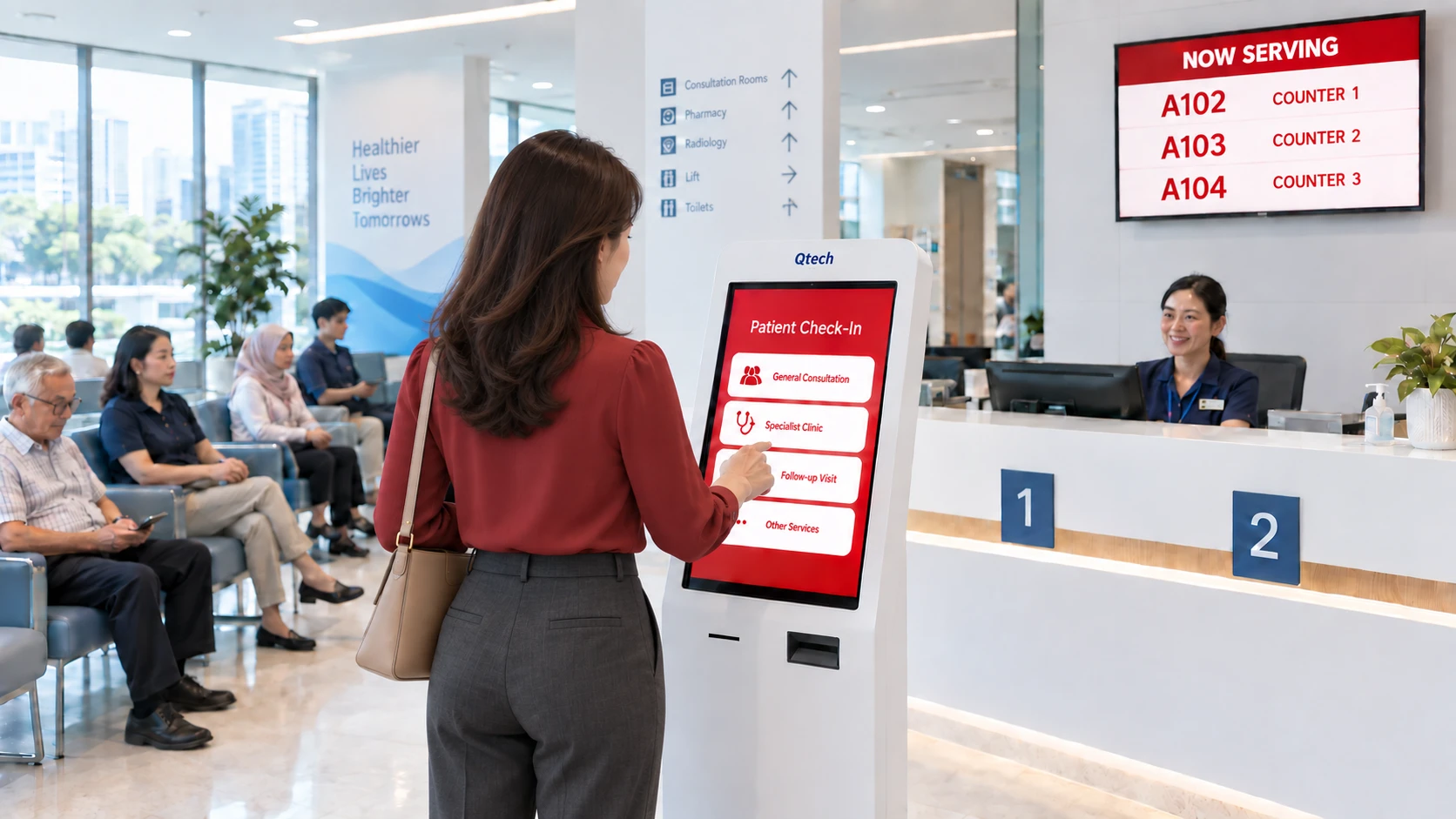 Patient checking in at a Qtech self-service kiosk while a Now Serving display calls queue numbers to counters
